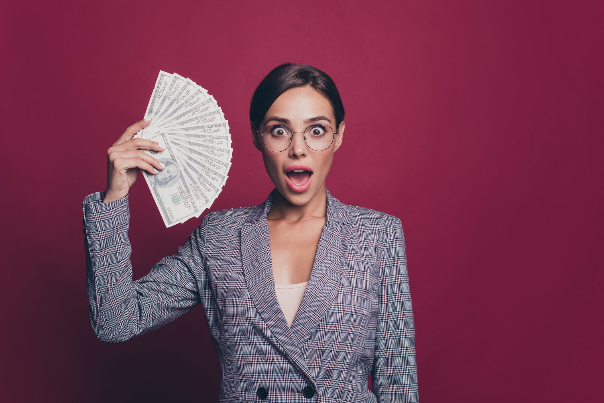 A woman holding up a fan of dollar bills.