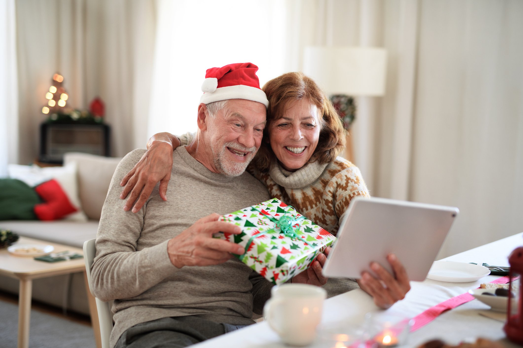 An older couple open a Christmas present while on a video call.