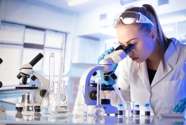 Scientist in lab looking through microscope