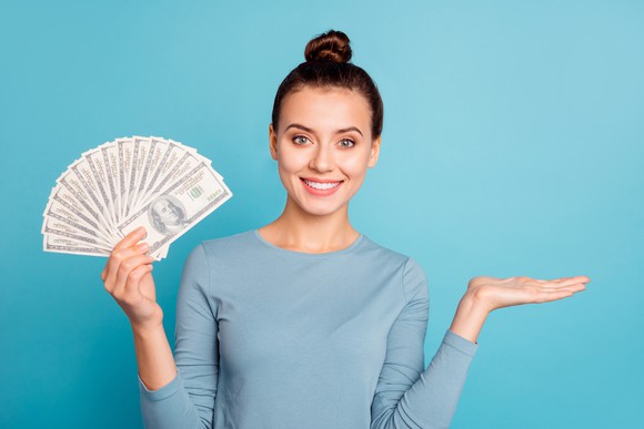 Woman holding fan of hundred dollar bills 