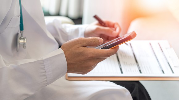 A doctor examines clinical trial patient data while holding his cell phone.