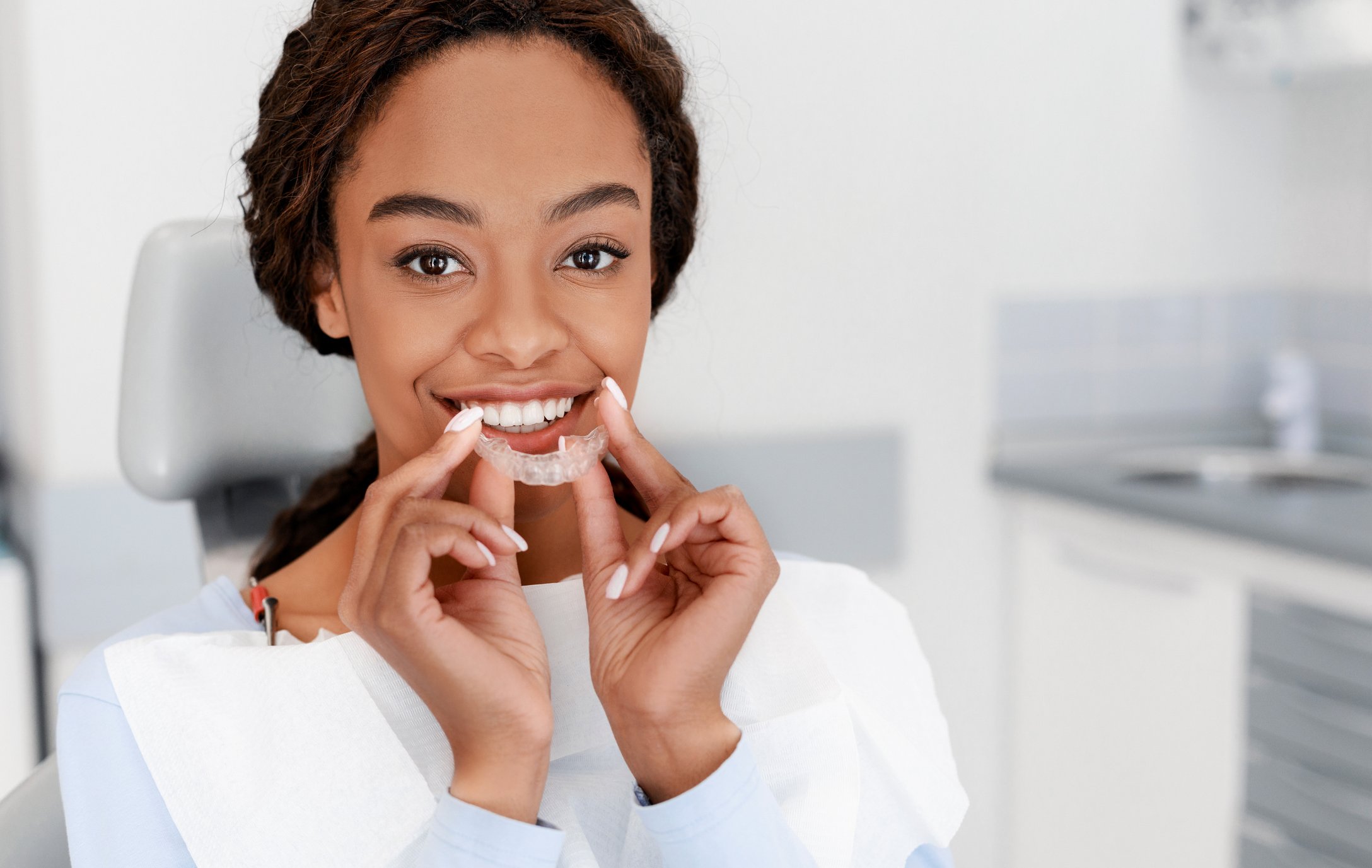 Smiling girl holding clear aligner