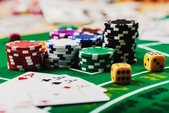 Poker chips, dice and playing cards on a green gaming table.