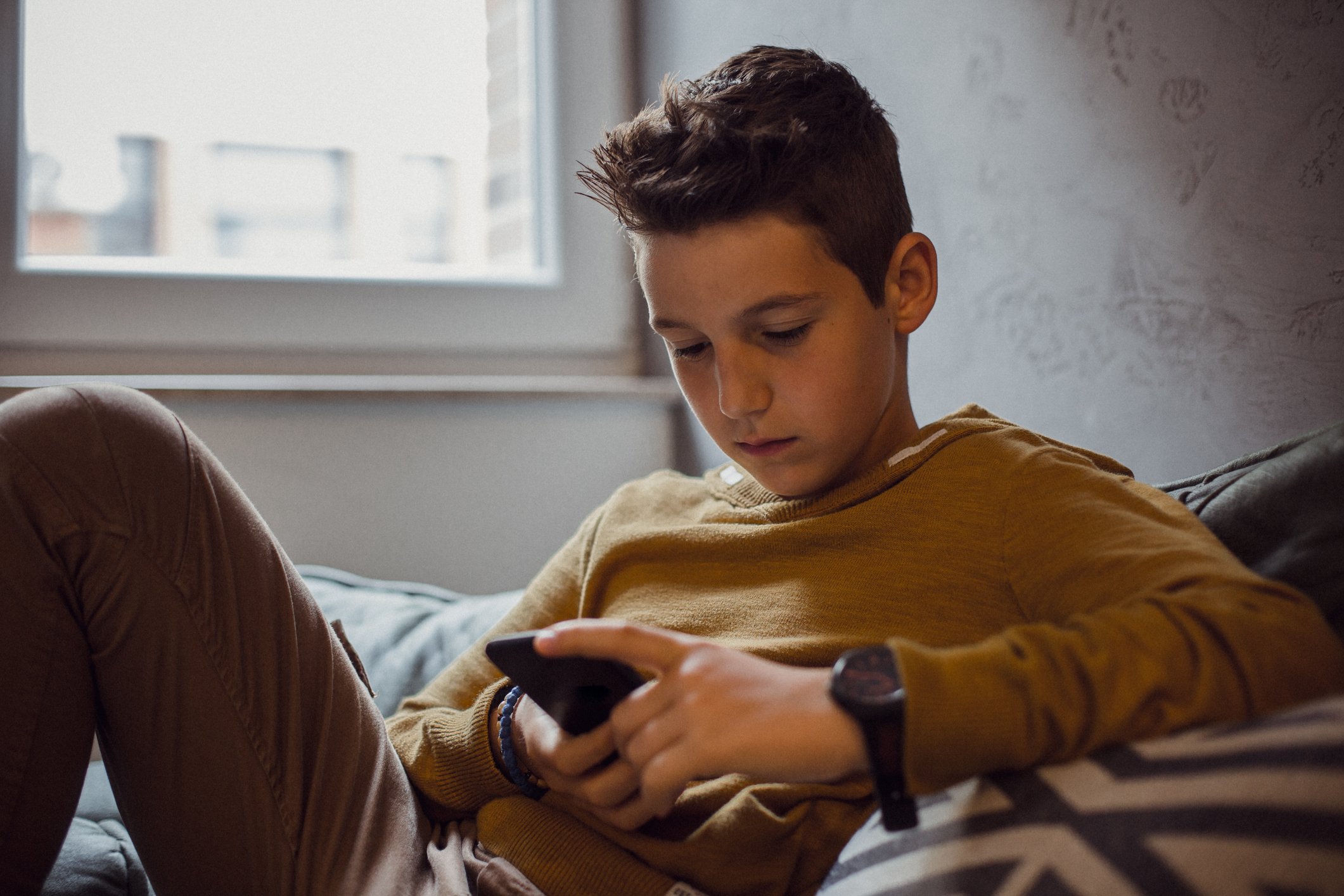 A teenage boy staring at his smartphone.