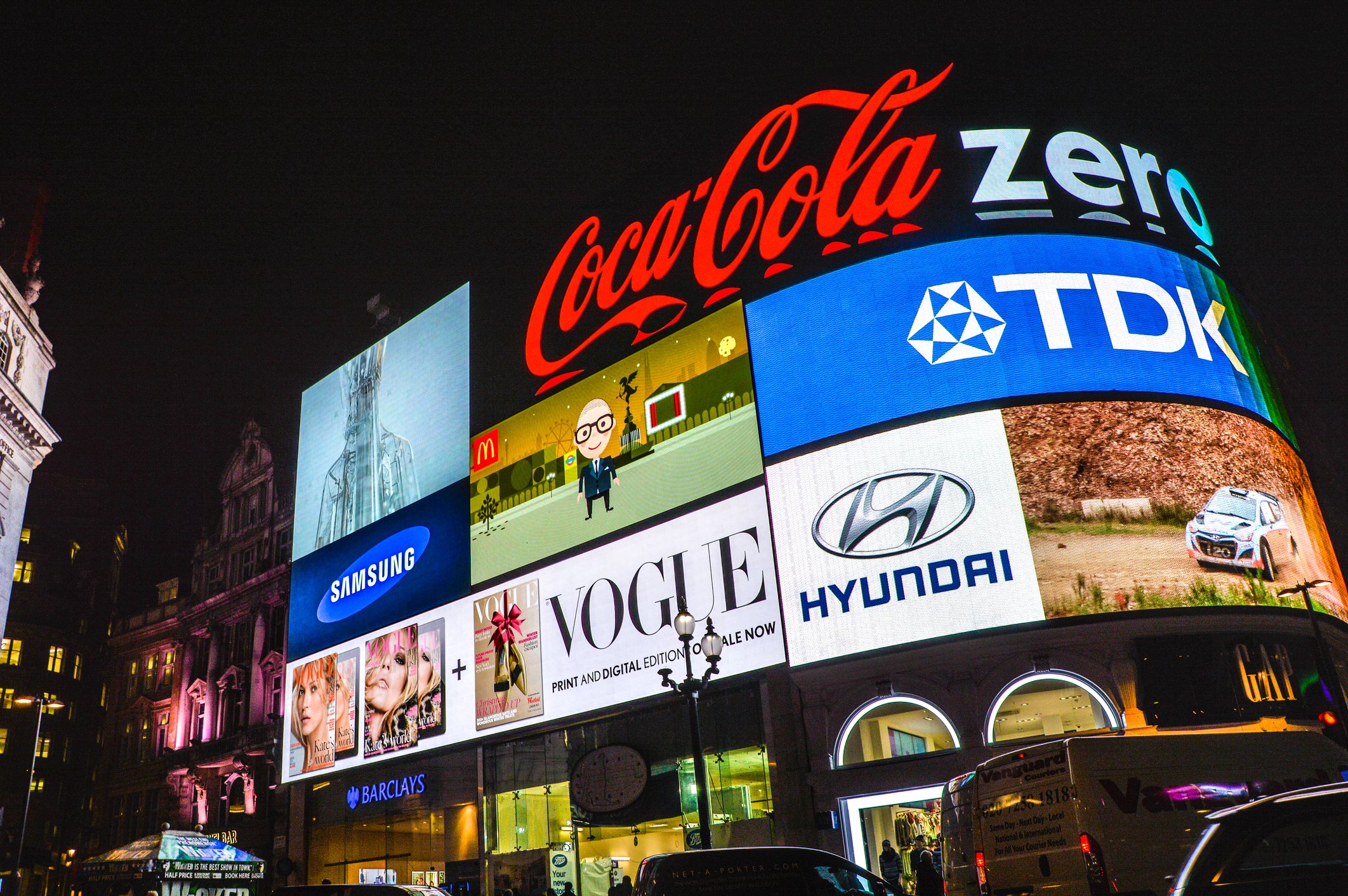 A Coca Cola advertisement lit up at night in Piccadilly in London, along with other brands.