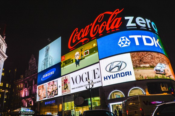 A Coca Cola advertisement lit up at night in Piccadilly in London, along with other brands.