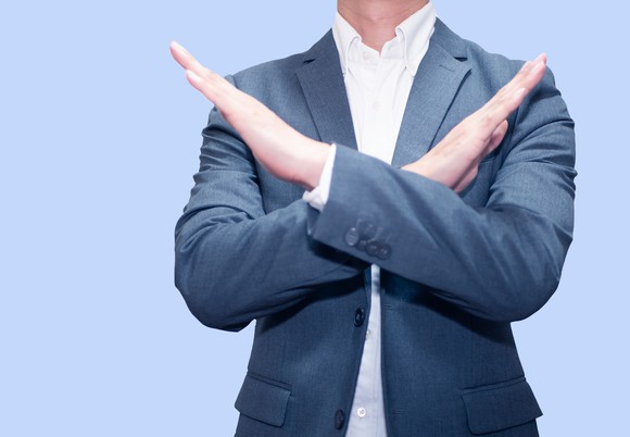 Photo of a businessman crossing his arms in a firm No gesture.