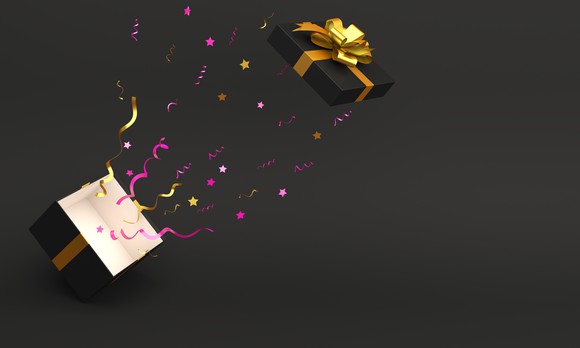 A gift box wrapped in golden ribbon launches off the top of a cube, leaving behind a trail of decorative items.