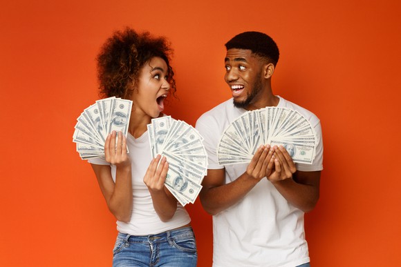 Stock photo of couple holdings cash bucks. 