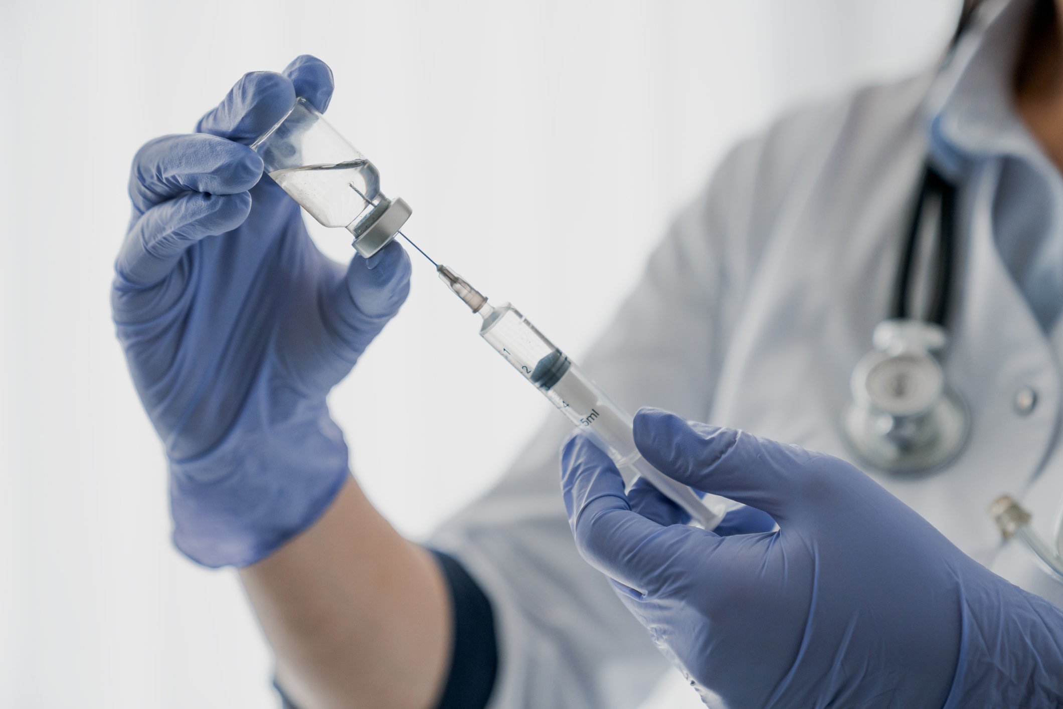 Physician holding syringe with a needle and a vaccine bottle