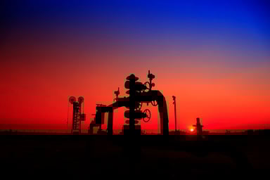 A natural gas well with pipelines at sunset.