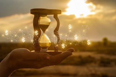 Hand holding hourglass with dollar signs