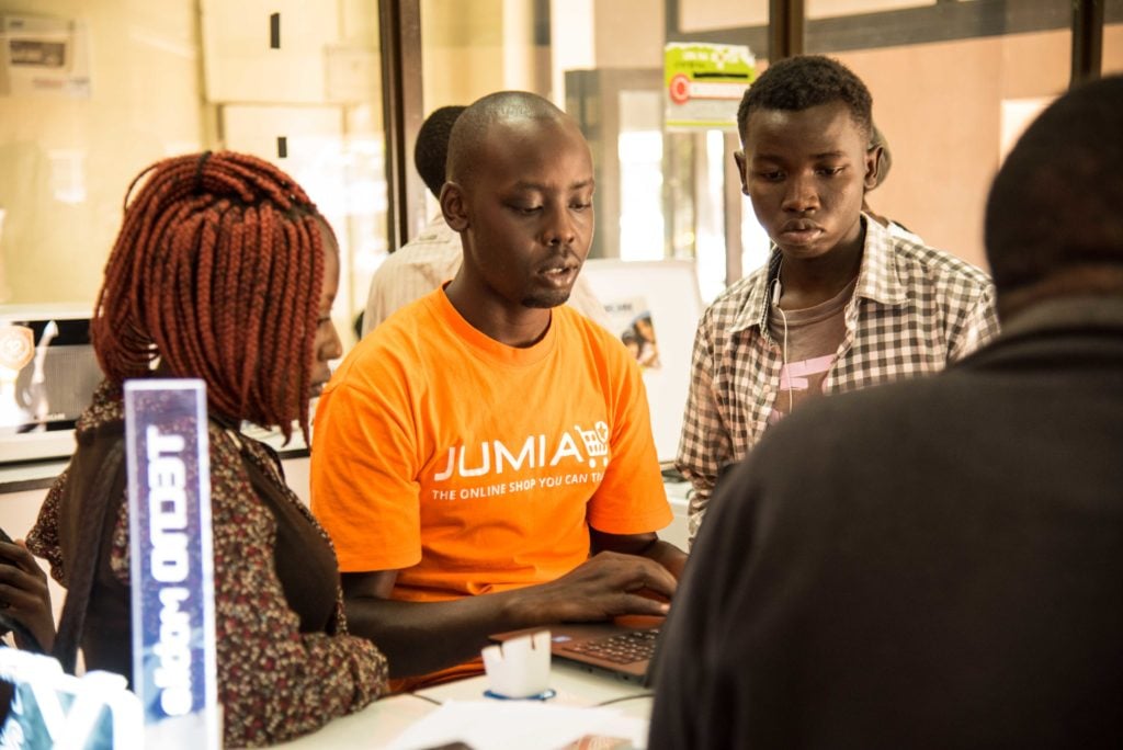 People from Jumia look at a computer screen inside a building.