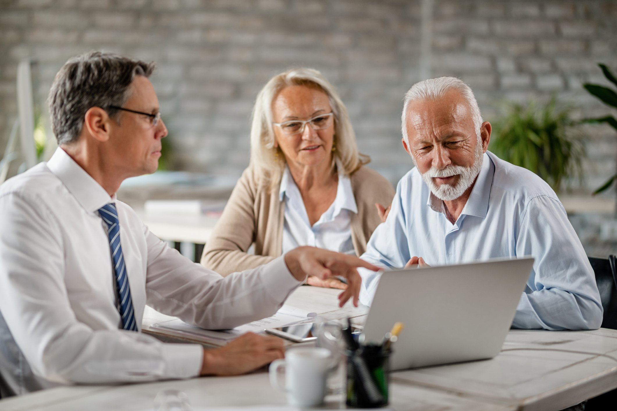 A mature couple looking at a laptop screen with their financial advisor 