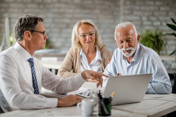 A mature couple looking at a laptop screen with their financial advisor 