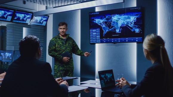 A soldier discusses a digital map in a briefing room.
