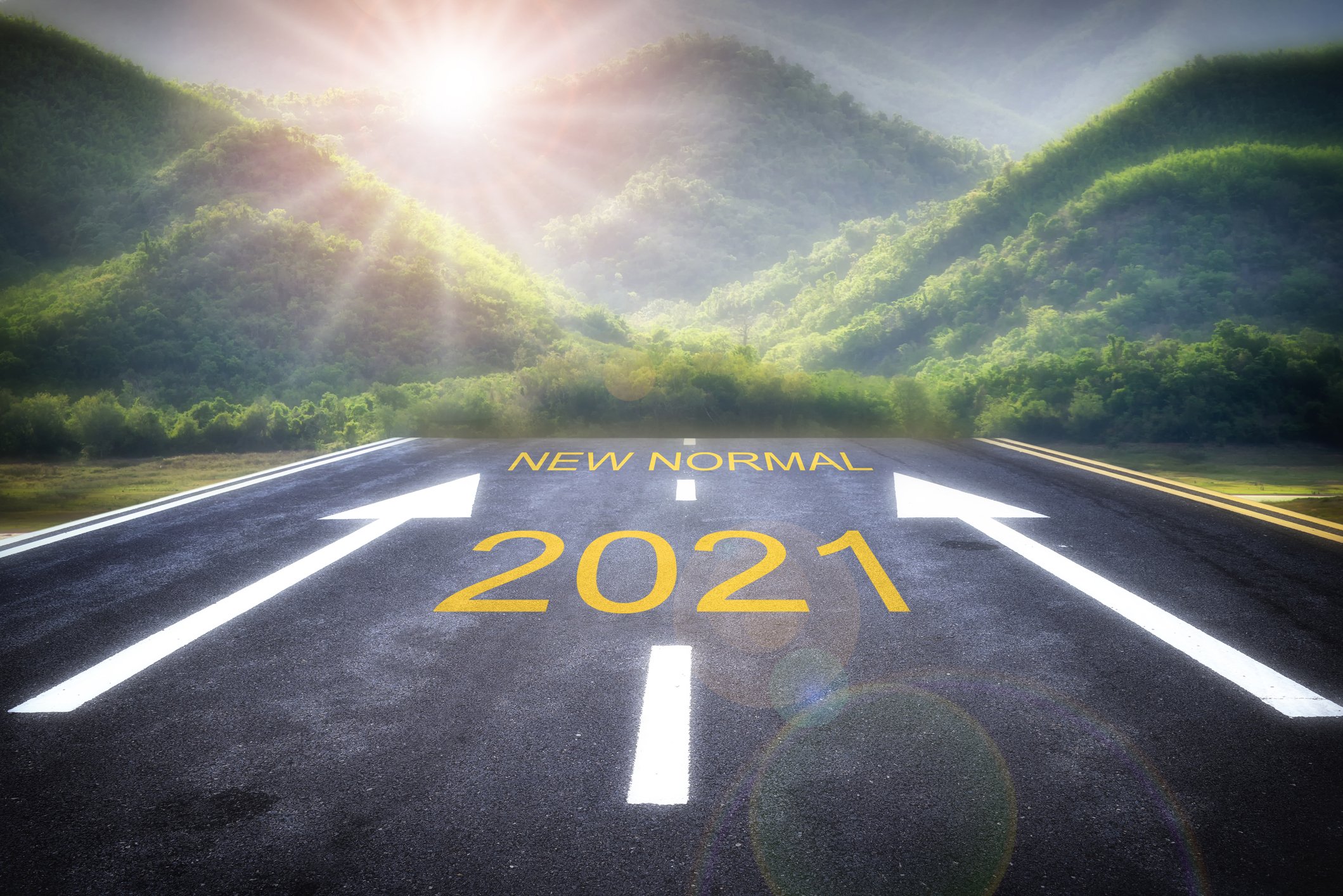 road with 2021 and arrows pointing to words new normal heading into green mountains