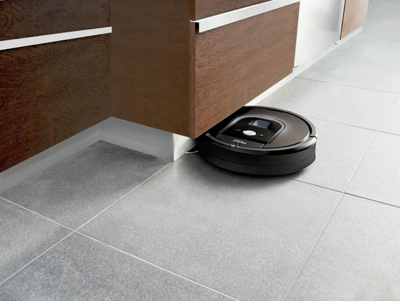 A Roomba vacuum cleaner cleans a tile floor.