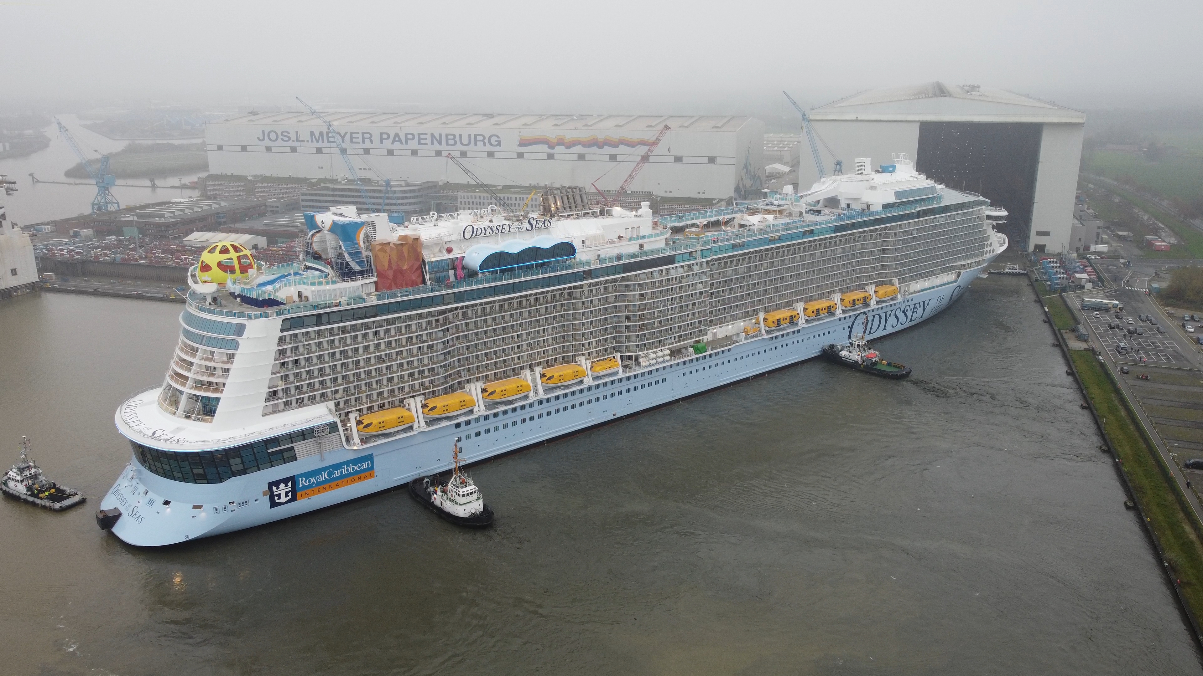 Odyssey of the Seas being moved by tugboats at its German shipyard.