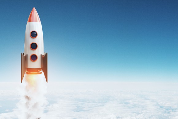 A toy rocket flies over the clouds.