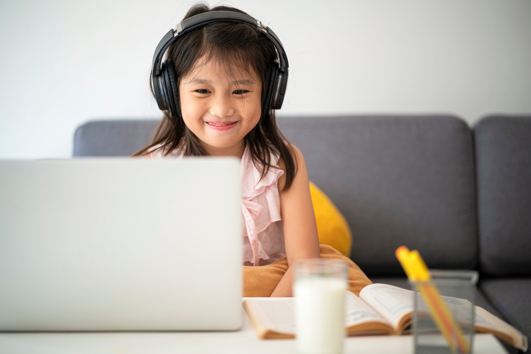 A young girl takes an online class on a laptop.