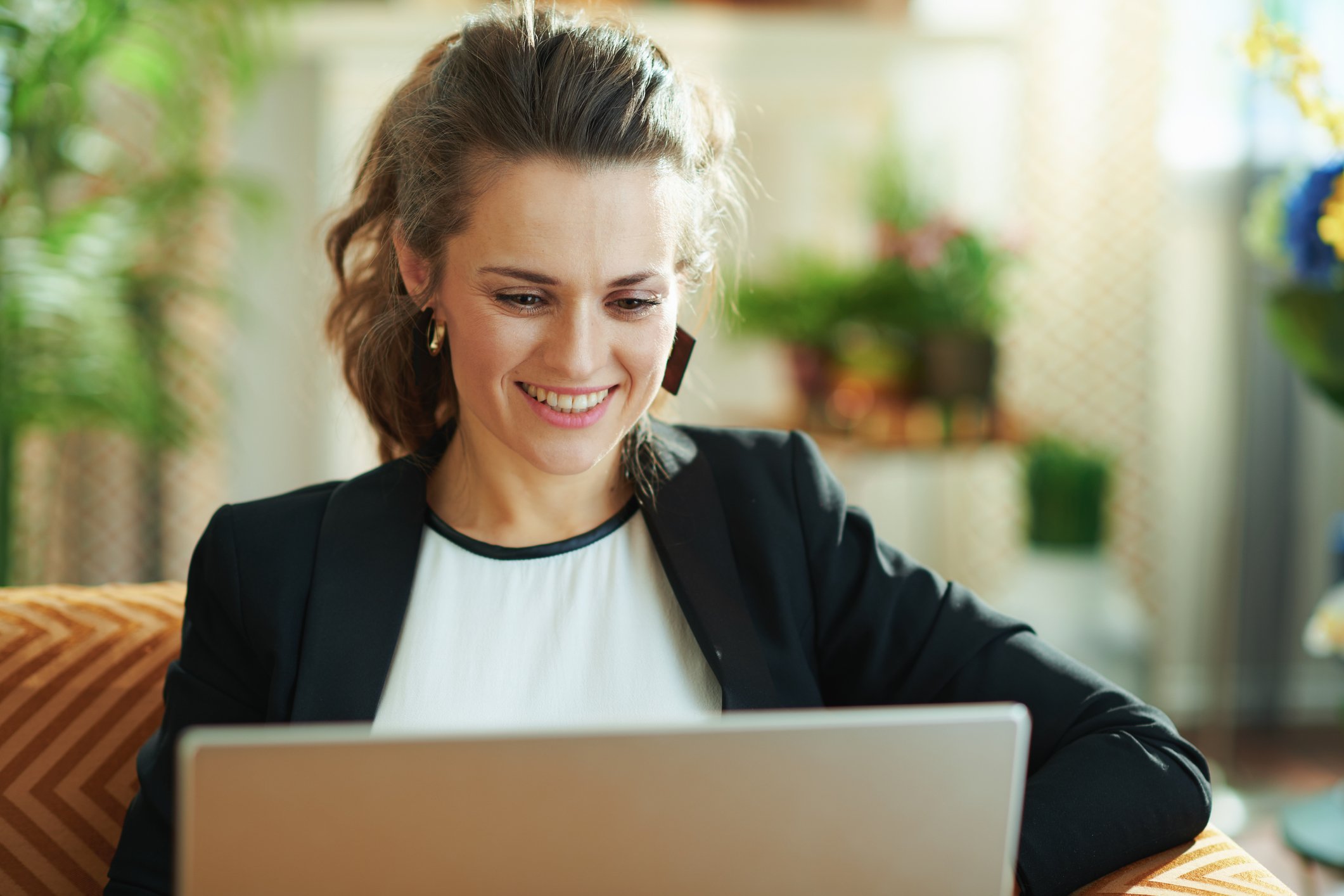 An investor smiles as she researches stocks on her laptop.
