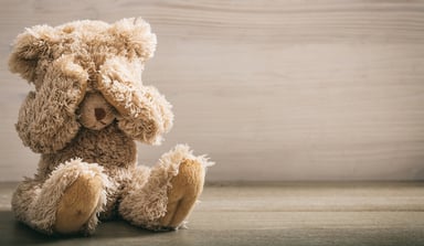 Frightened teddy bear covers its eyes