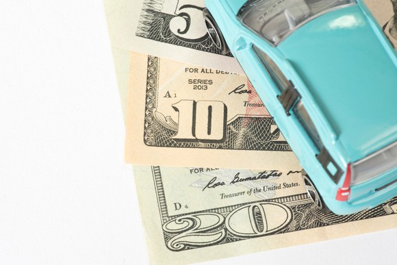 Illustration of a vehicle driving over currency.
