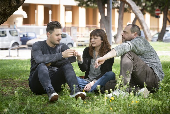 three people sitting in a park smoking marijuana