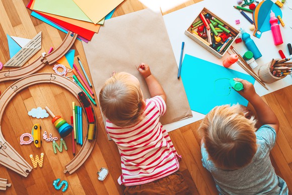 Two kids drawing on the floor