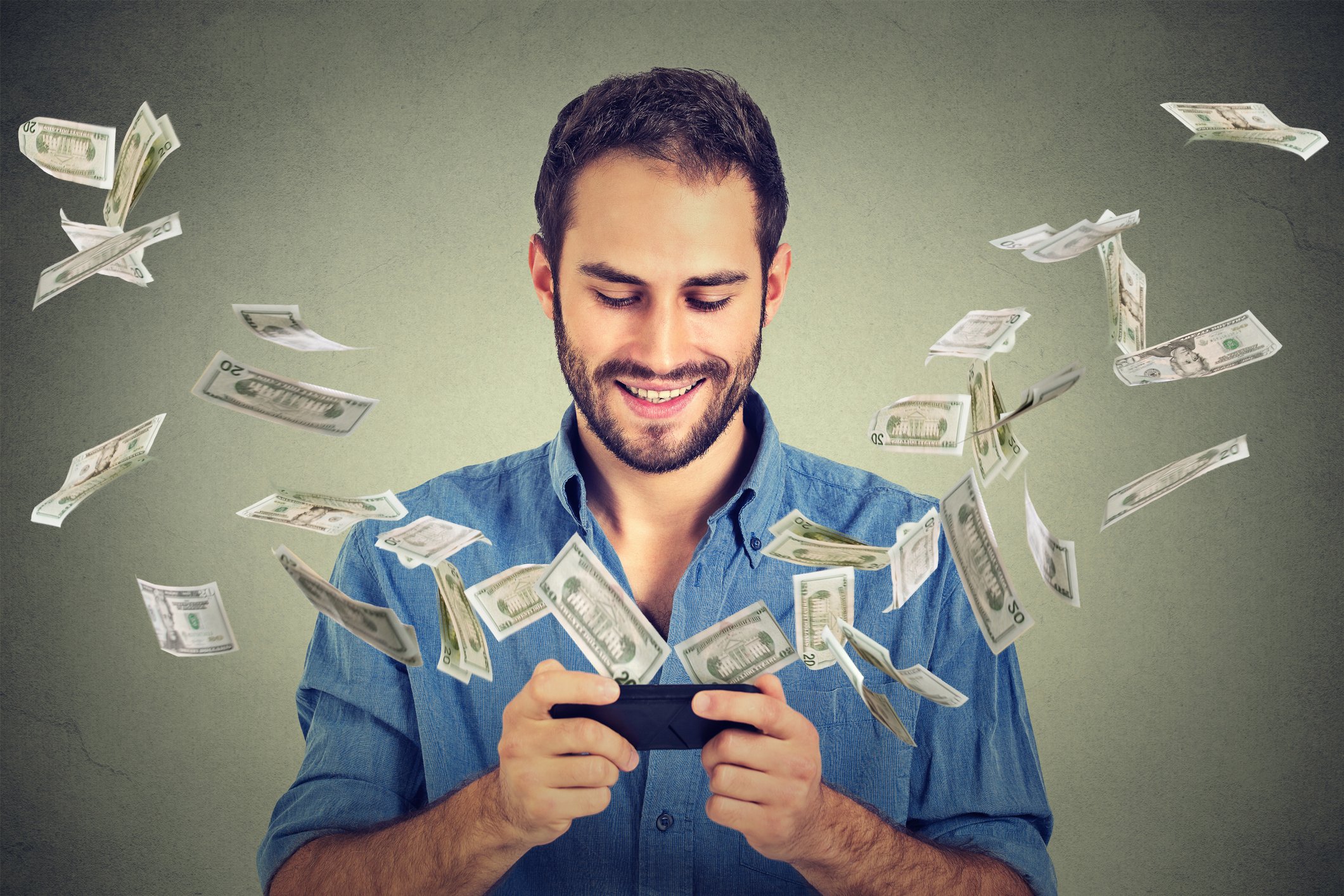 Man grinning while cash flies from his smartphone.