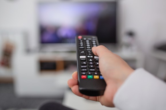 A person pointing a remote at a TV.