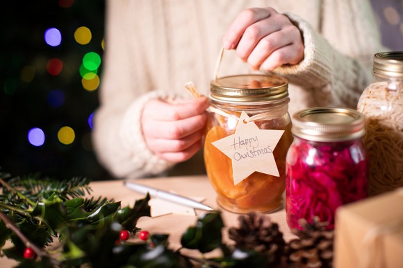 Person putting finishing touches on a personalised gift in a jar.
