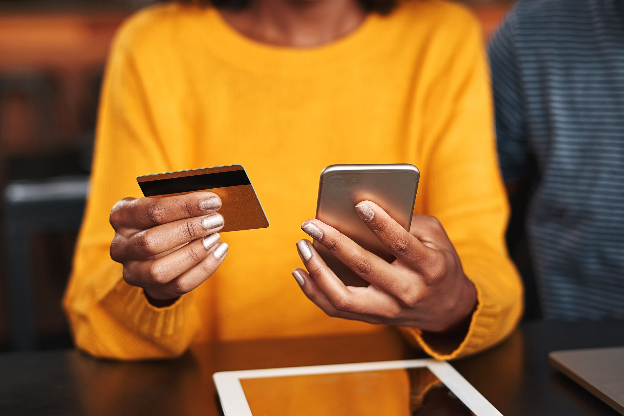 A woman holding a credit card and a mobile phone.