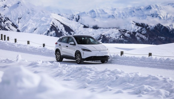 An XPeng electric vehicle driving on a snowy road. 