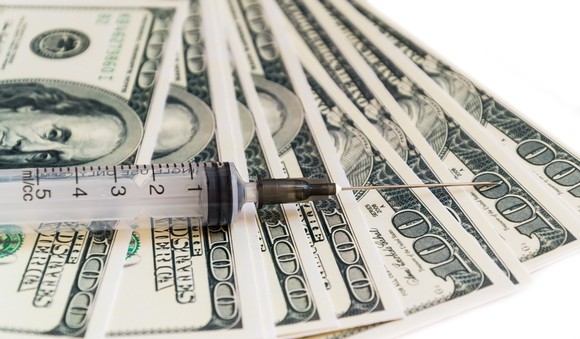 Syringe with needle on top of $100 bills