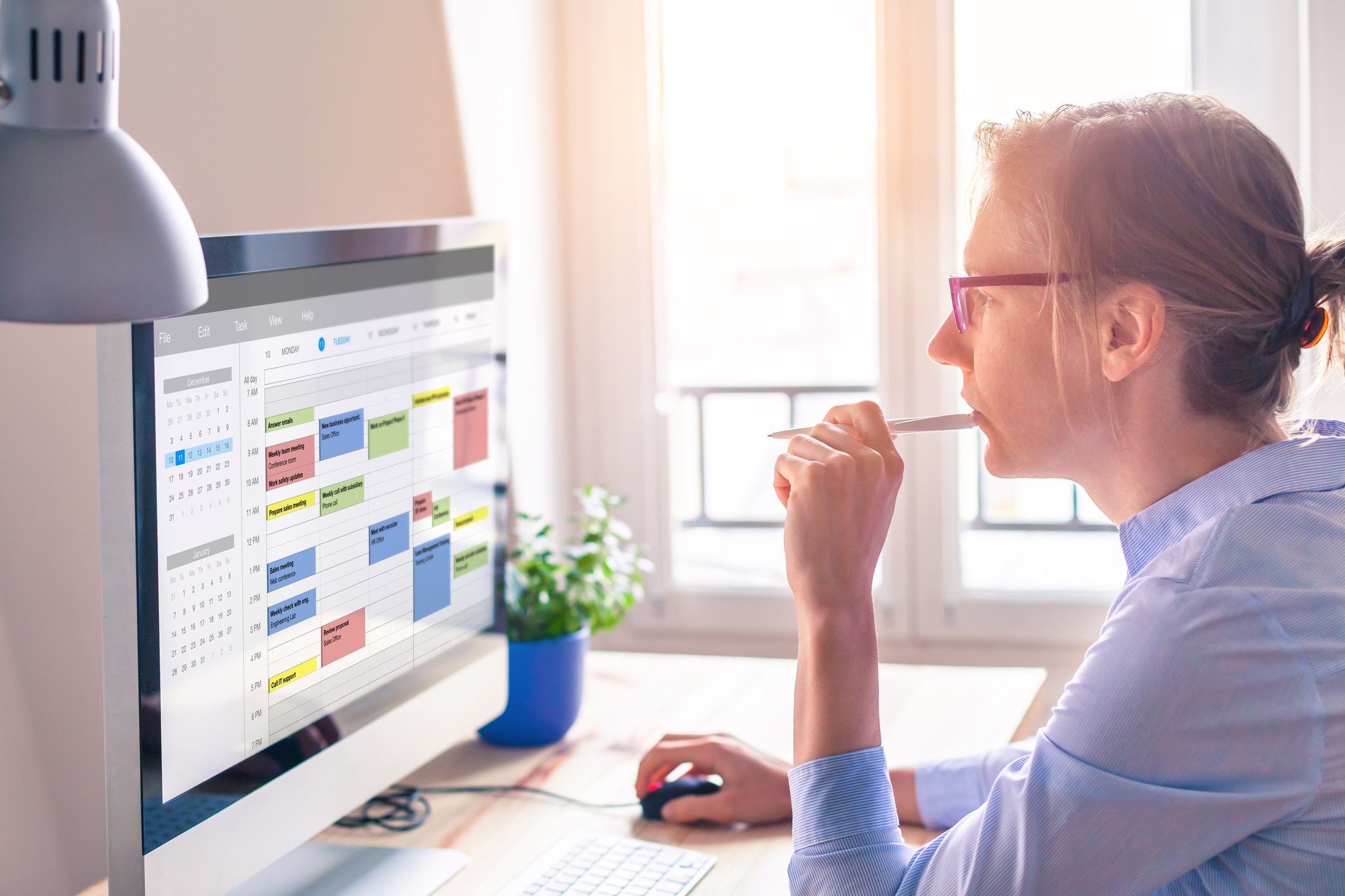 Woman biting on pencil while looking at computer screen