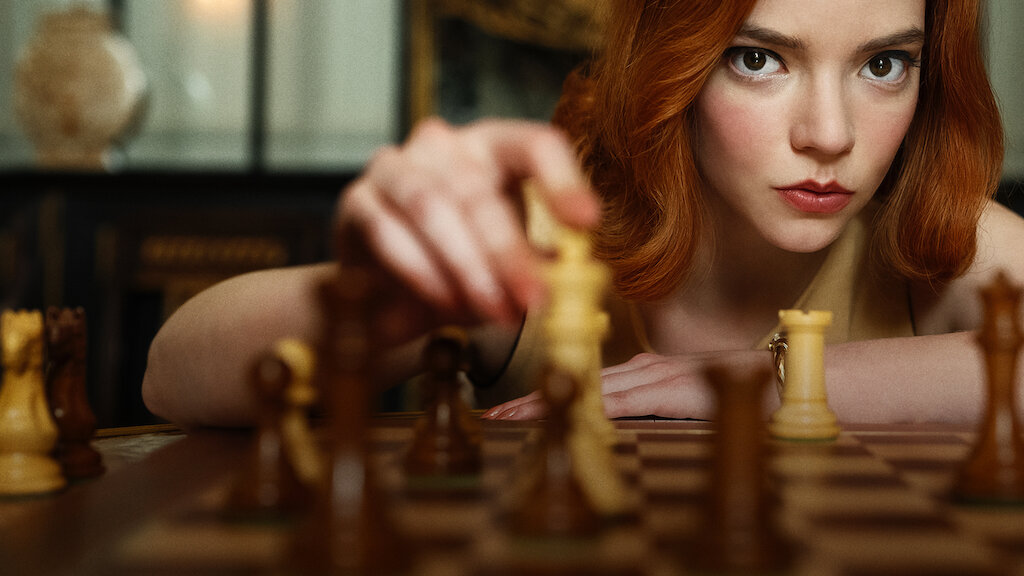 The Queen's Gambit star Anya Taylor-Joy holds a chess piece on the chess board.