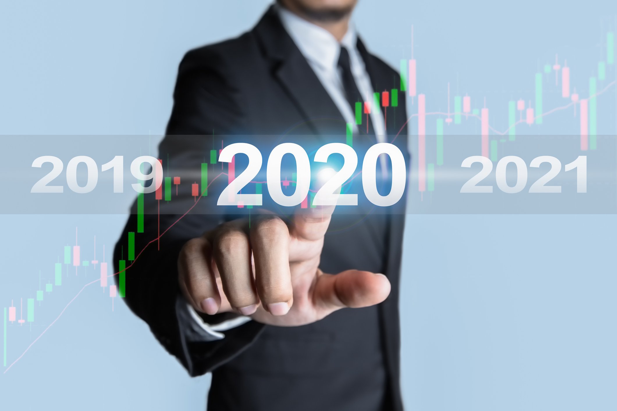 Man pointing at screen with rising stock chart and "2020" on it