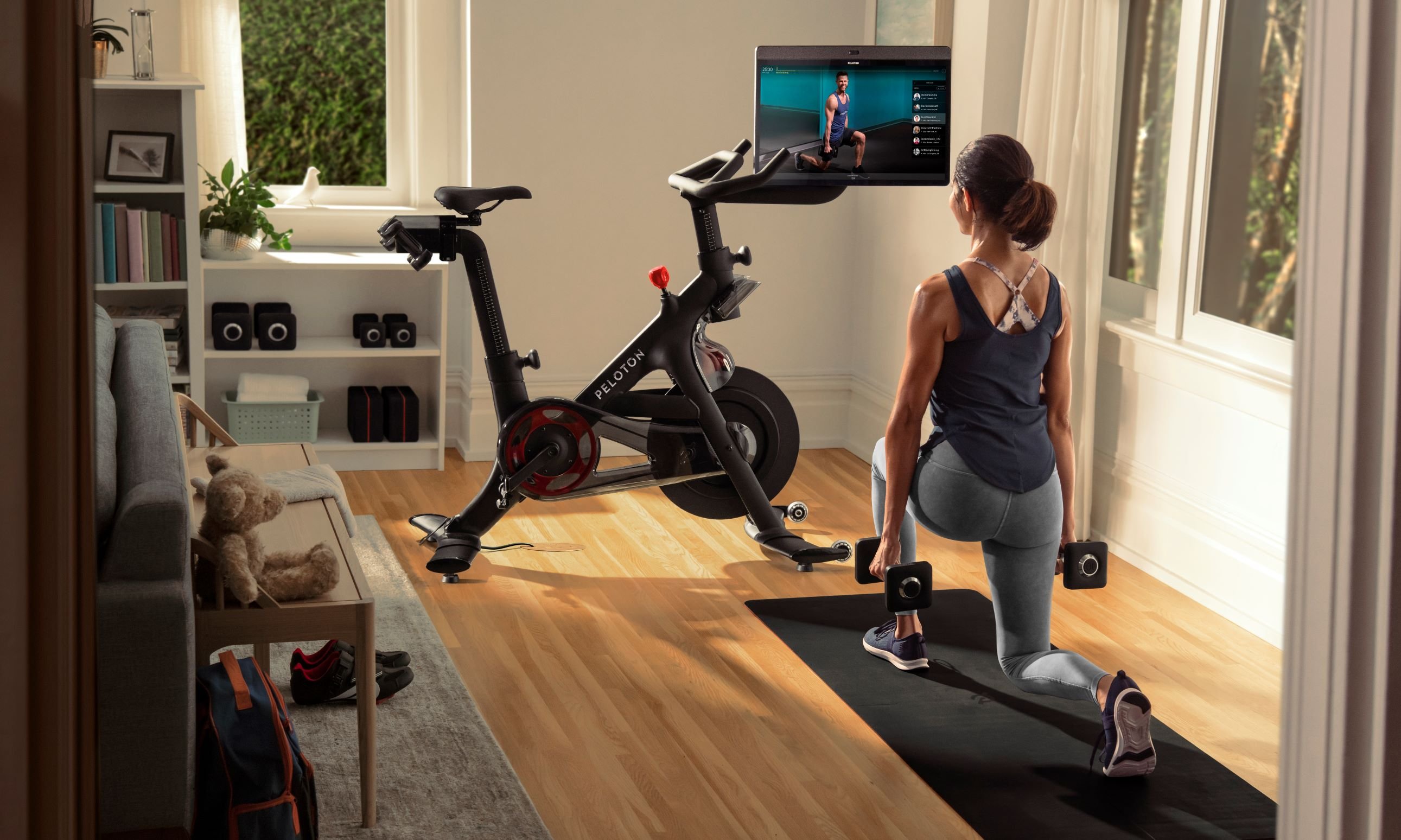 Woman exercising with Peloton bike nearby.