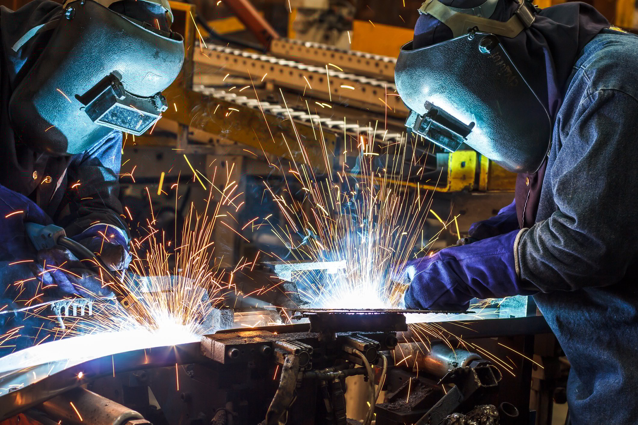 Steelworkers work on finishing steel in a manufacturing plant.   