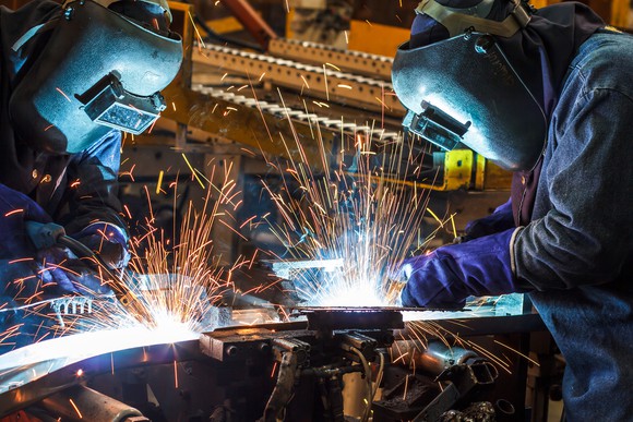 Steelworkers work on finishing steel in a manufacturing plant.   