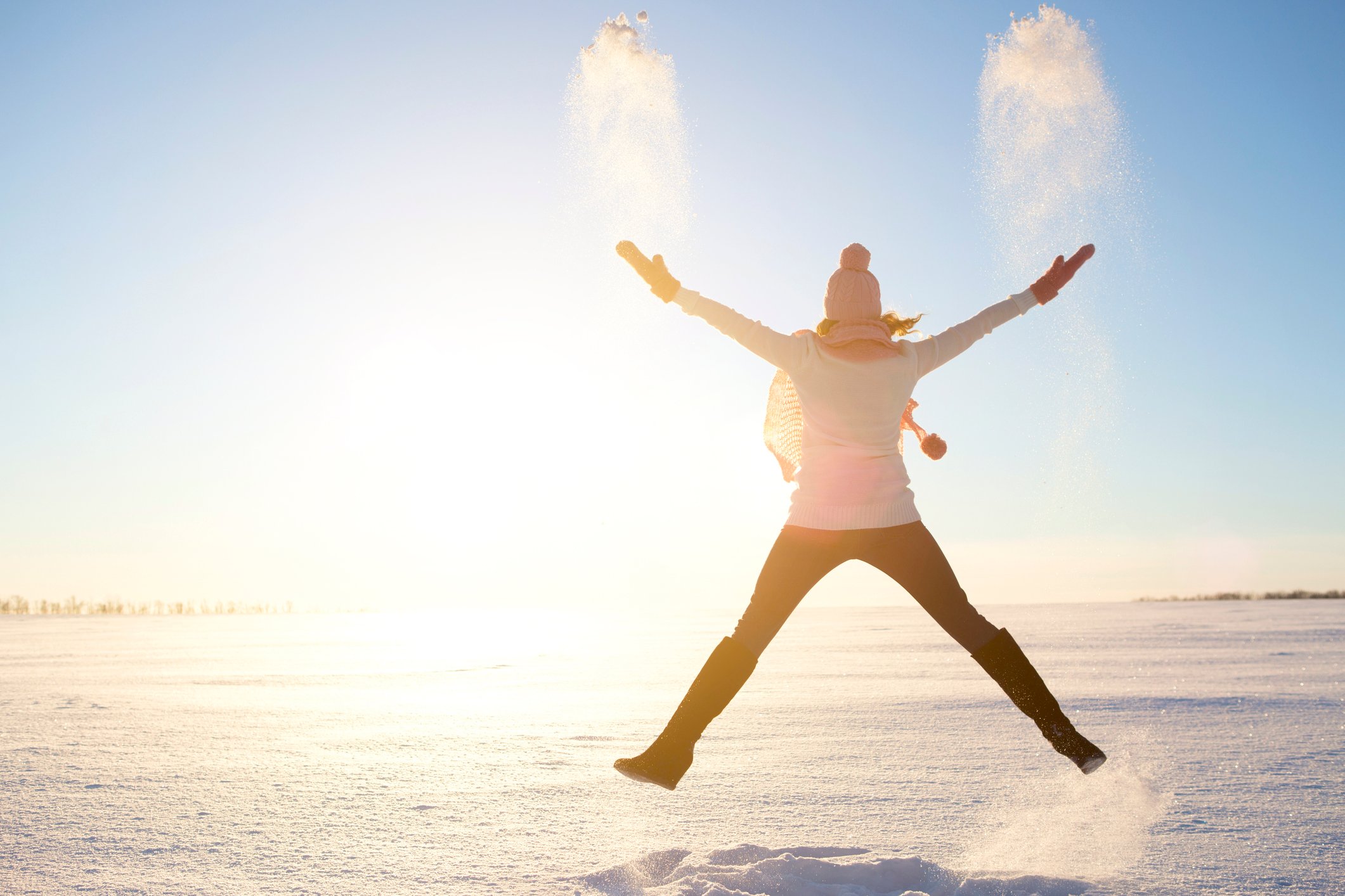 Woman in a winter landscape jumping triumphantly.