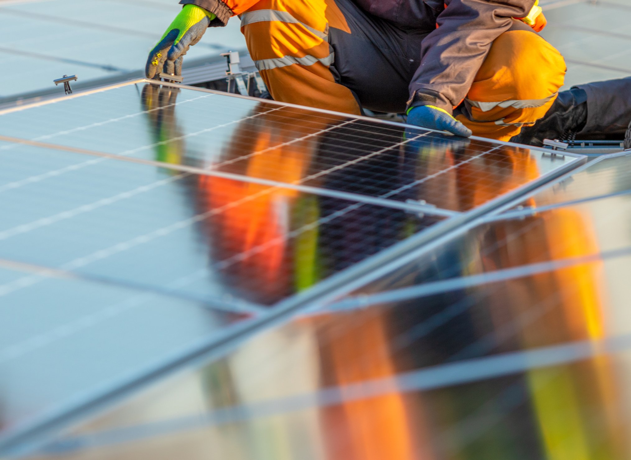 A worker lays down a solar panel on a rooftop. 