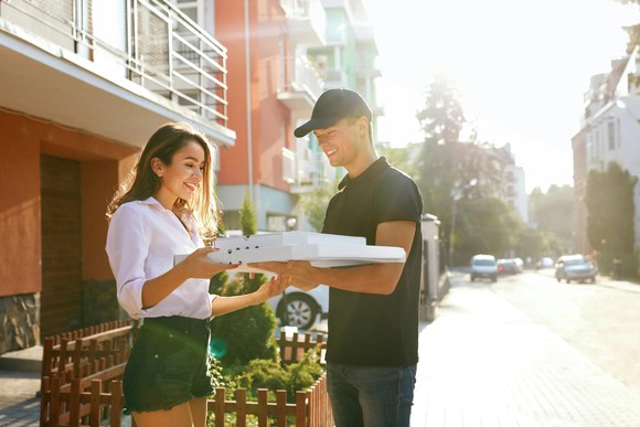 Delivery person giving another person delivery boxes.