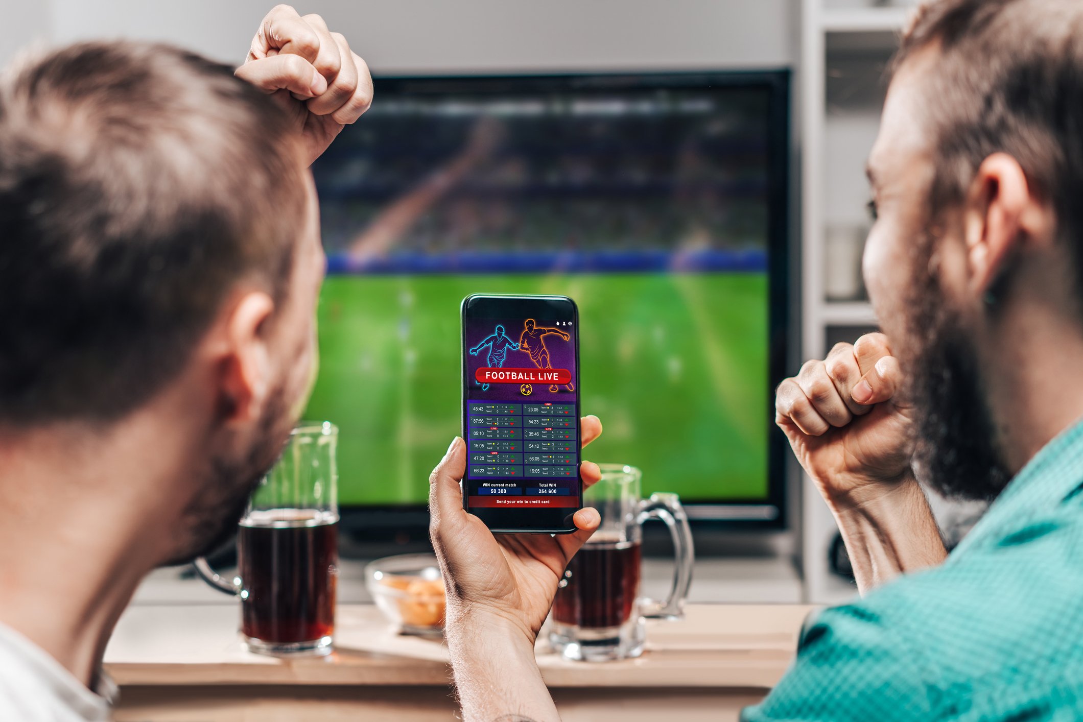 Two people betting on live sports on a mobile device. 