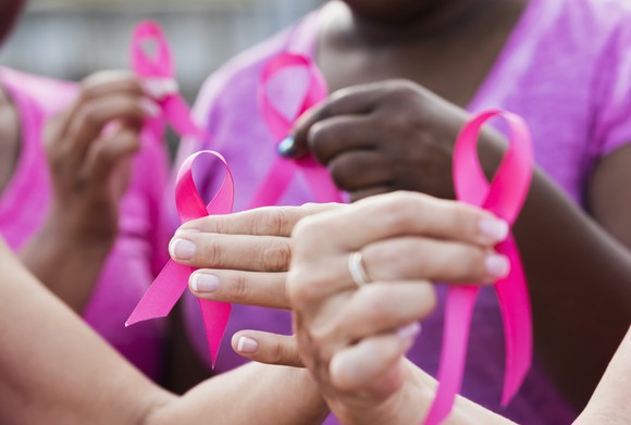Medical workers hold pink breast cancer ribbons