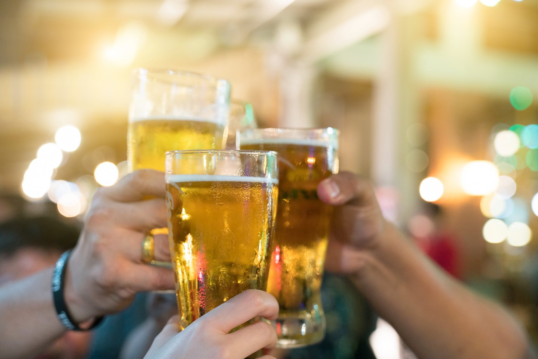 Three beer drinkers clink their glasses.