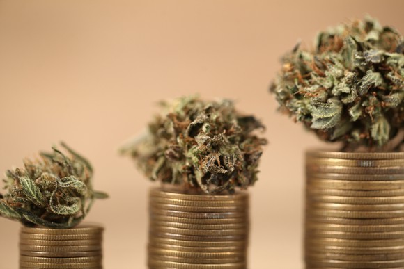 Marijuana is on top of rising stacks of gold coins. 