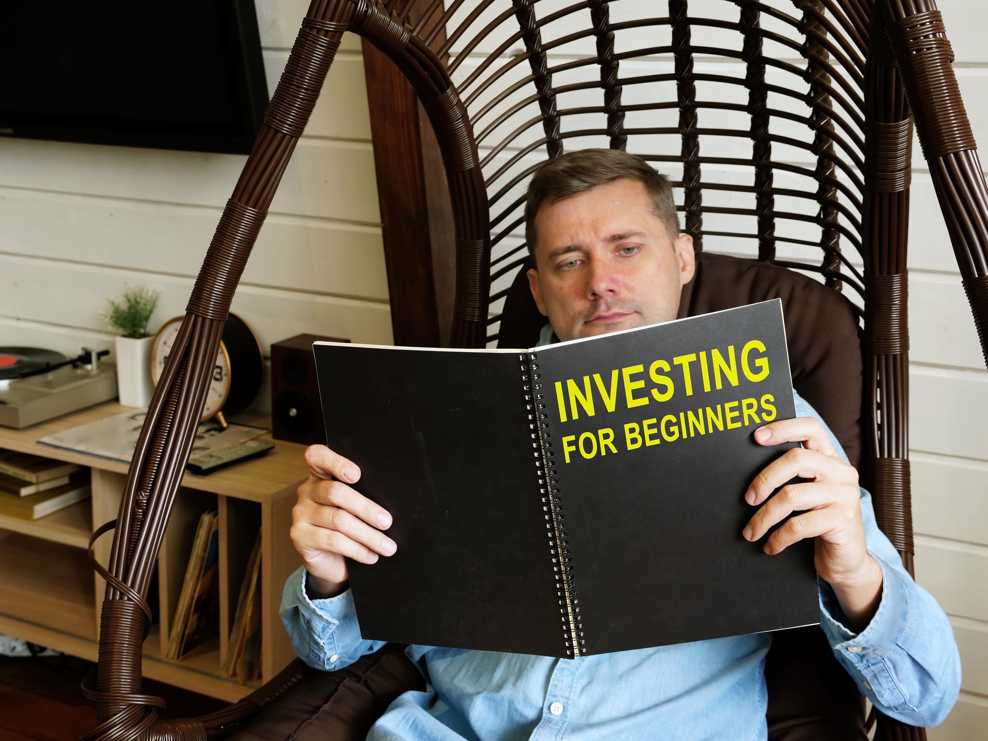 A man reading a book called Investing For Beginners.